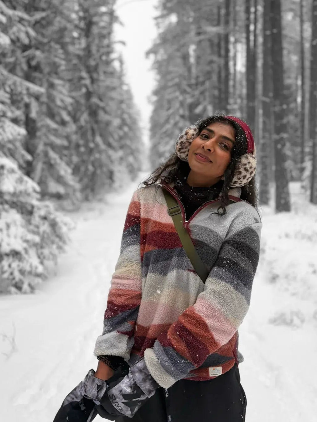 Person wearing a colorful striped sweater in a snowy forest