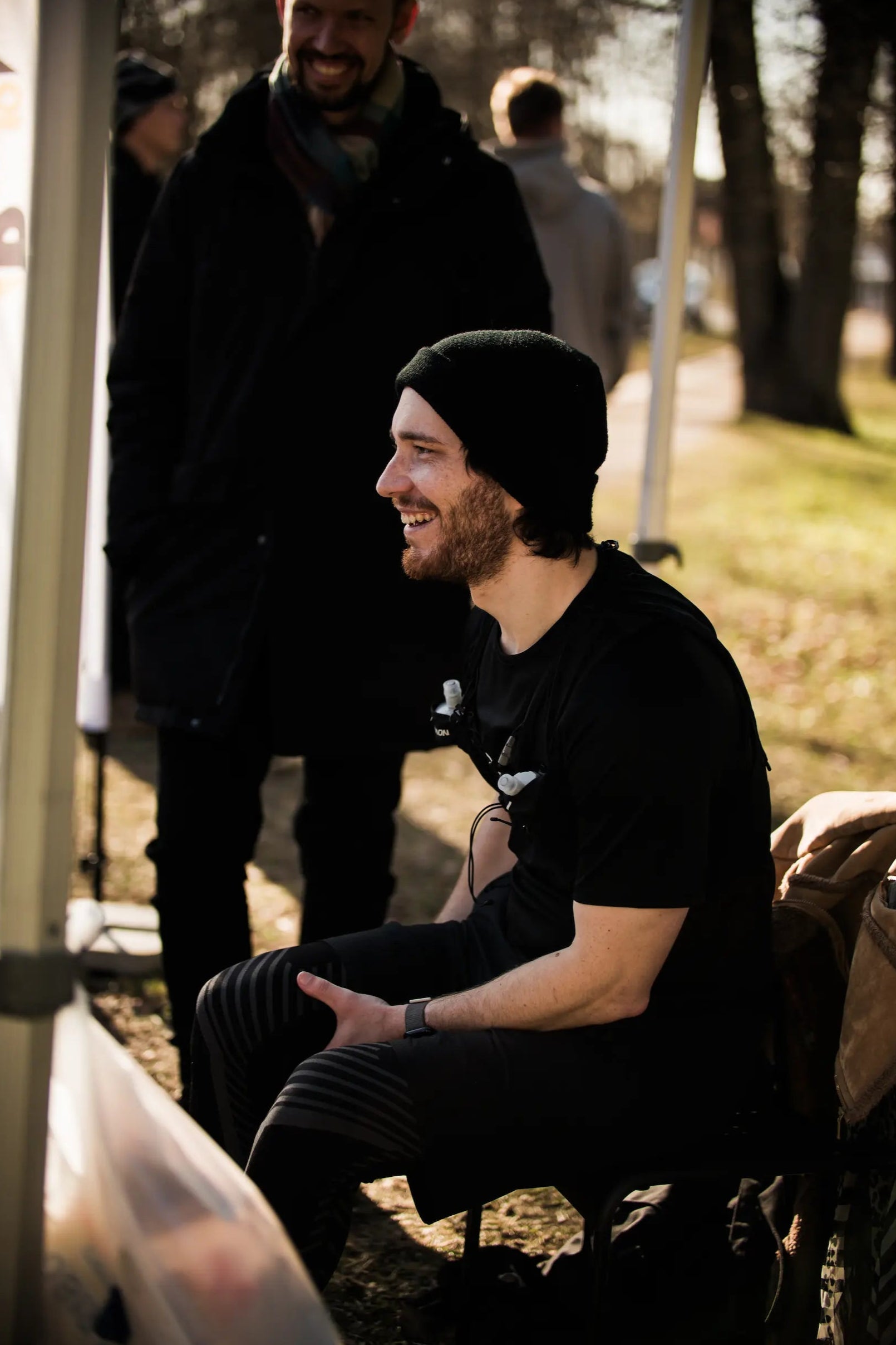 Man sitting down during a 100km ultramarathon another man standing beside him