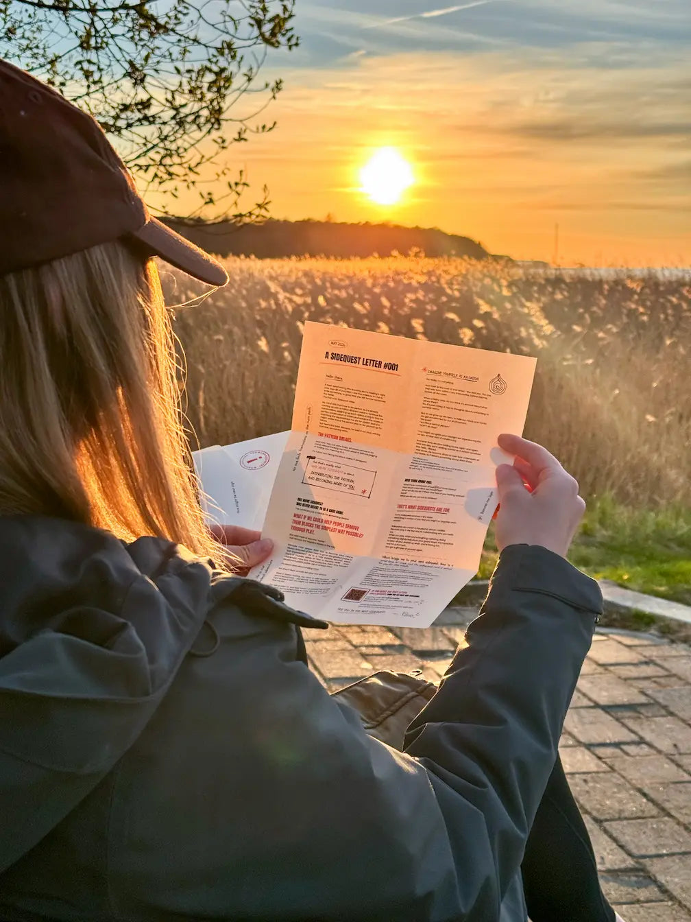Person reading a monthly adventure letter from Sidequest Mail Club at sunset