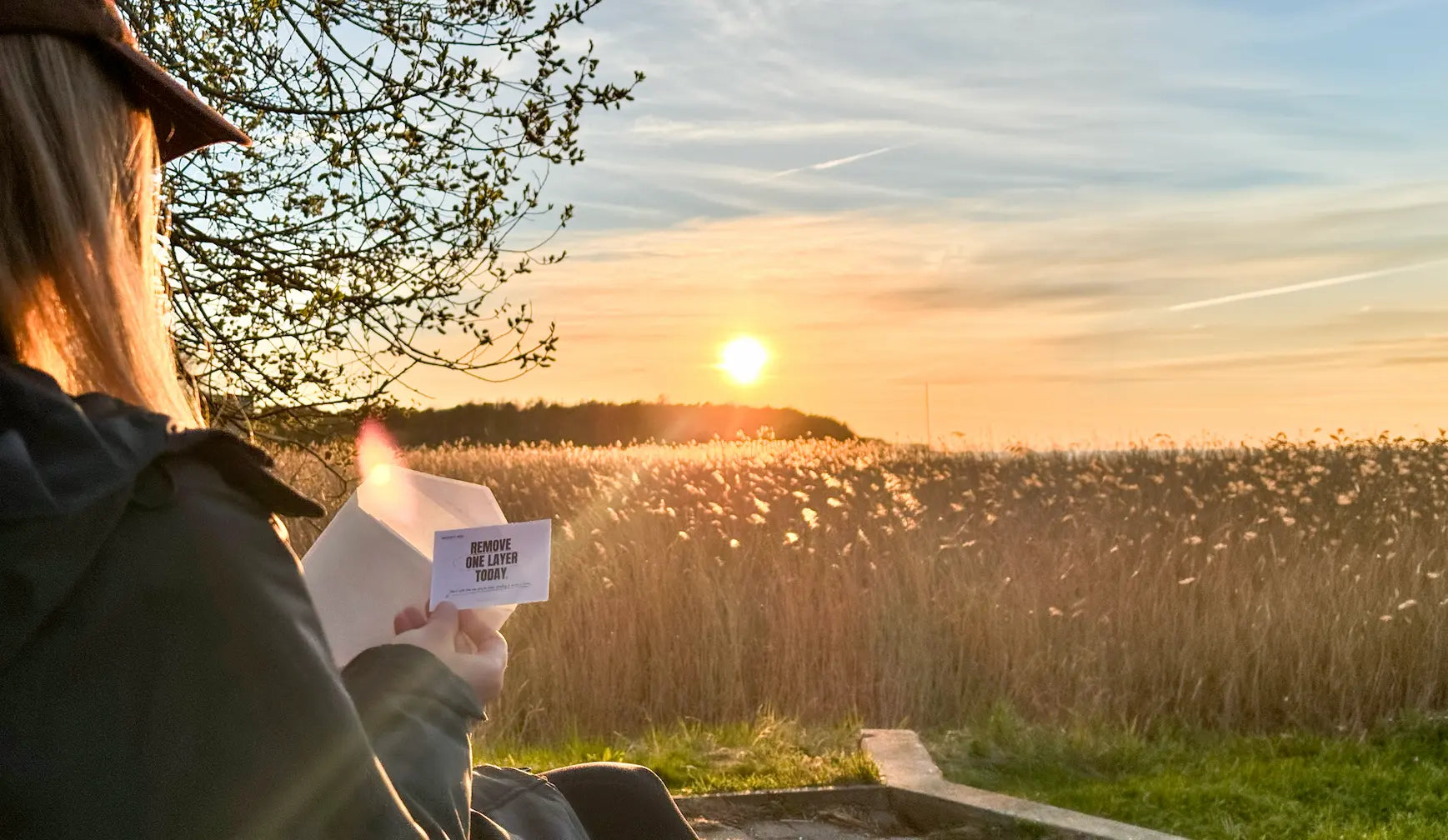 Person opening a Sidequest Mail Club letter outdoors at sunset