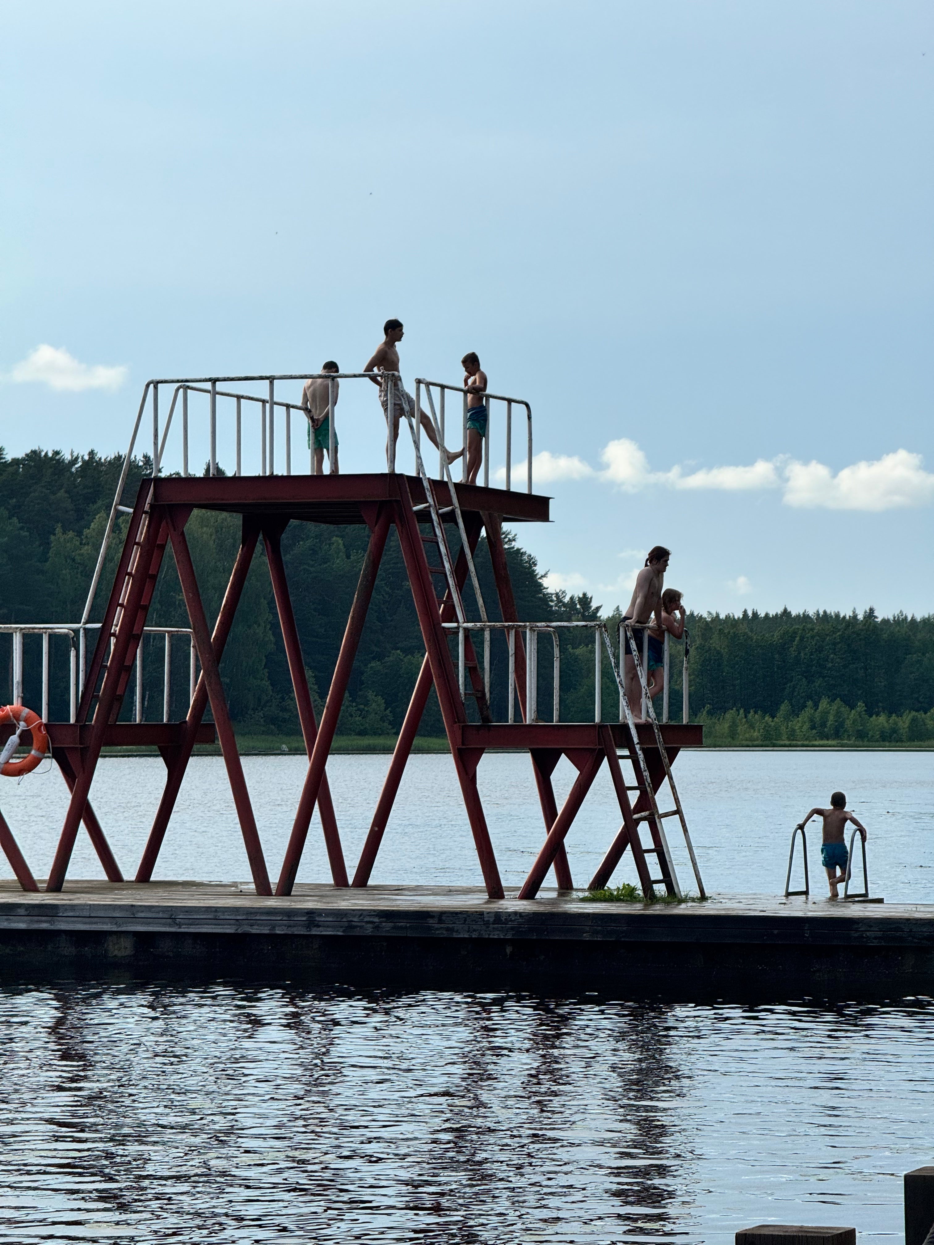 People standing on a lake diving platform before jumping into the water